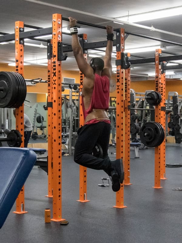 a gym member does weighted pull ups during a strength training workout at a gym near me in albany ny
