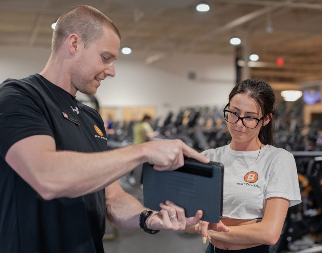 personal trainer advising gym member on progress