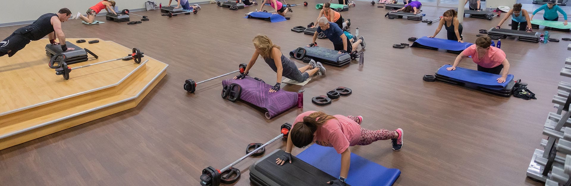 large exercise class in spacious modern gym doing pushups