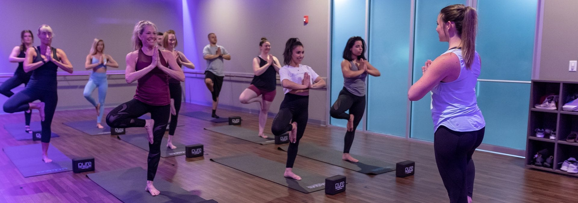a group of people doing stretches in a spacious and modern hot yoga studio with ambient lighting in the best gym in danvers