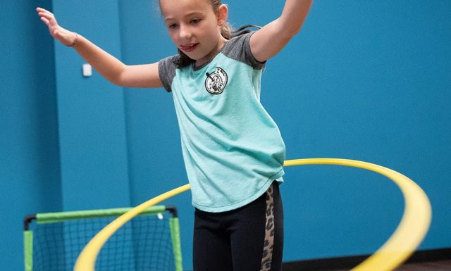 a young girl in a kids club playing with a hula hoop in the best gym near me