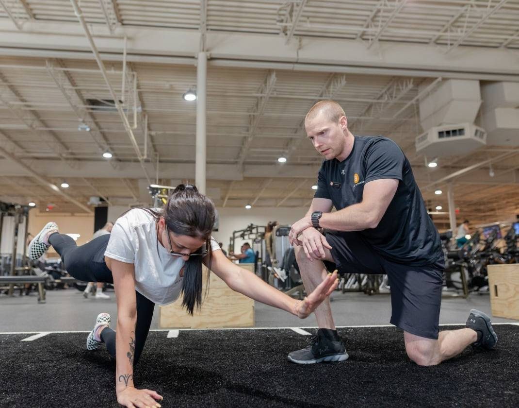 personal trainer helps woman achieve fitness in clean modern gym near me