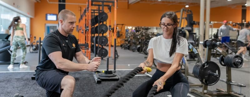 a certified personal trainer guides a gym member during a weighted rope workout at a best fitness gym near me
