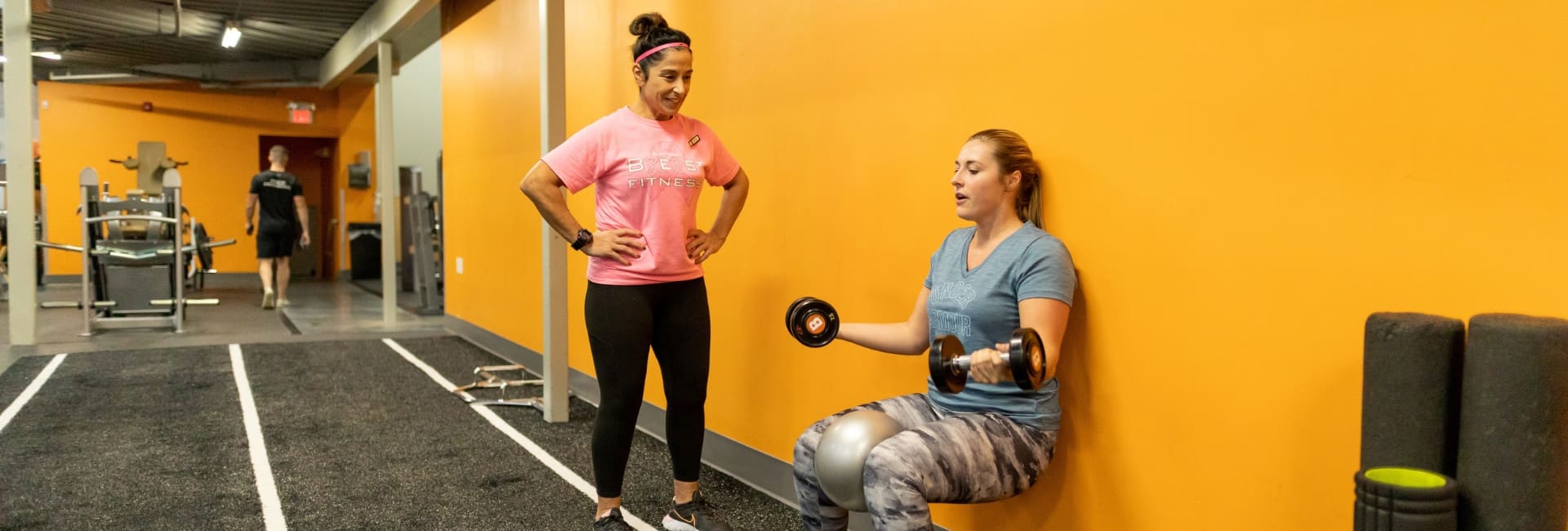 a gym member does wall sits during a personal training session at best fitness gym in lowell ma