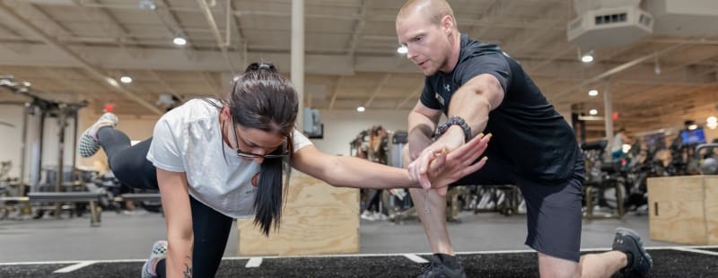 a personal trainer works with a gym member for a core workout at best fitness gym in lowell