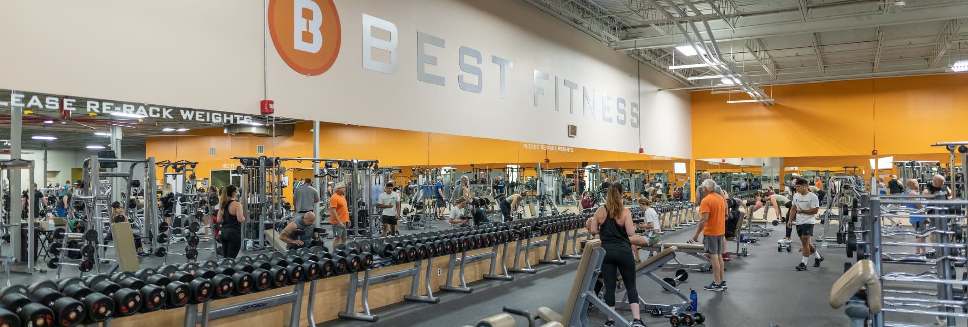 gym members use free weights for strength training in a spacious weight area at a best fitness gym near nashua