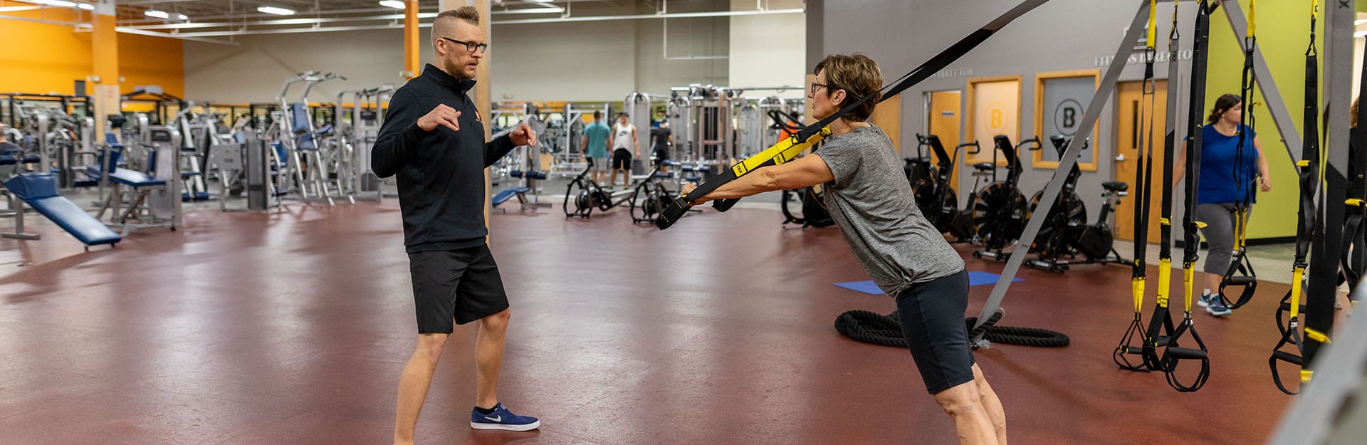 personal trainer coaching a gym member on trx bands