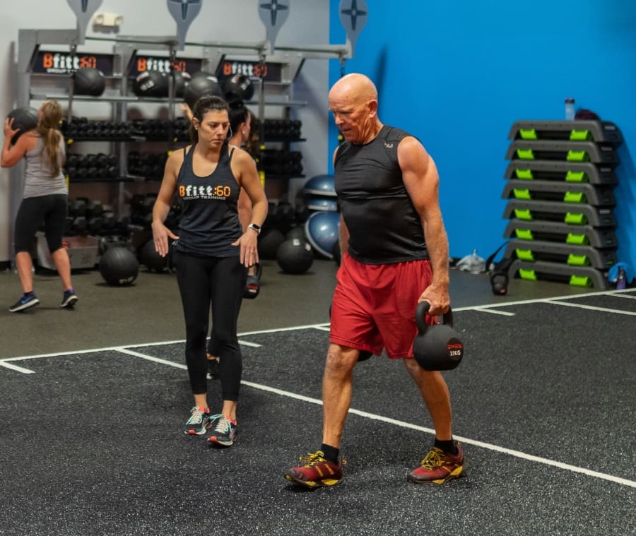 a gym member does weighted lunges with a personal trainer at best fitness gym near me