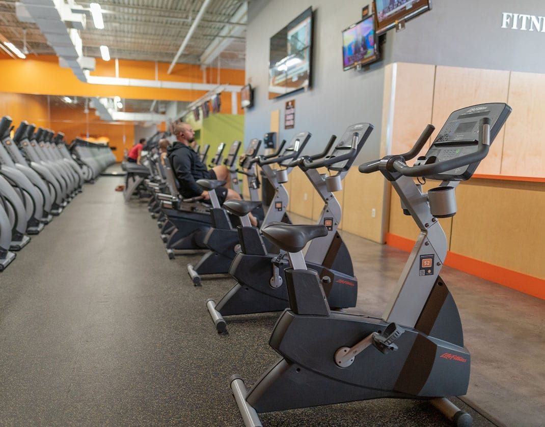 row of cycling machines on cardio floor with tvs