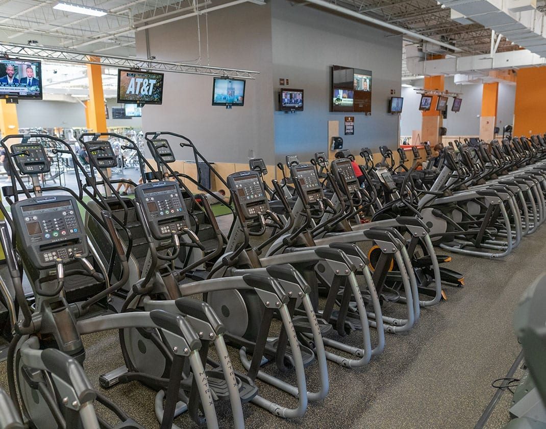 rows of cardio equipment with tvs hanging from ceiling