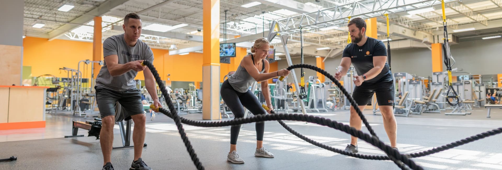 gym members work with a personal trainer during weighted rope workout at the best gym near me