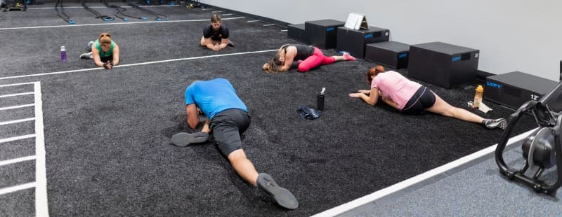gym members stretch in a group fitness studio at best fitness gym near me