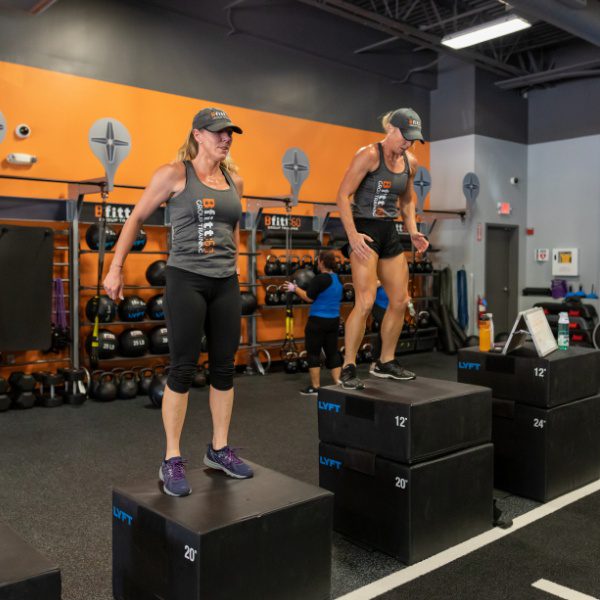 2 ladies do box jumps during an intense group fitness class at a woburn best fitness gym