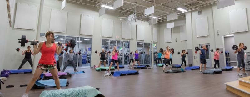 gym members lift free weight barbells during a group fitness class at a best fitness gym near me in woburn