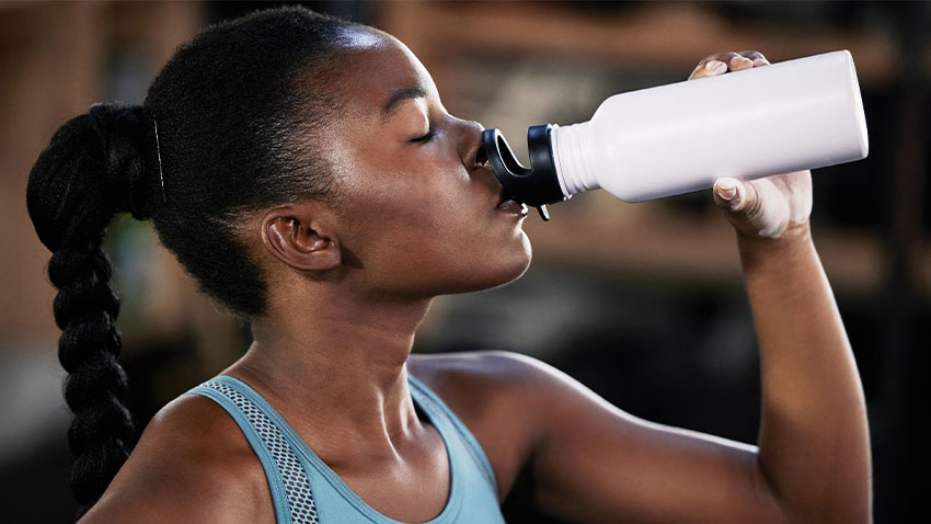 woman drinking water in a best fitness gym near me