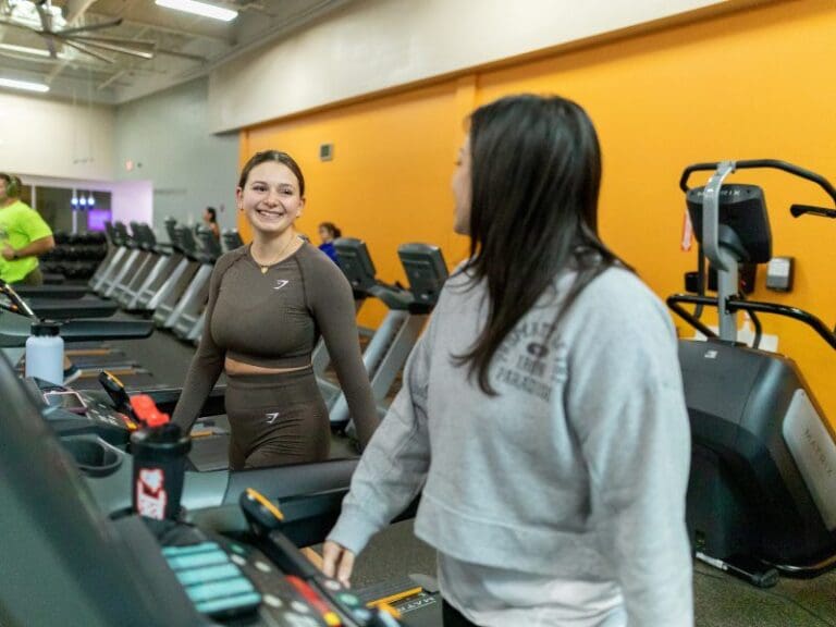 gym members talk during a cardio workout on treadmills at a modern gym near me
