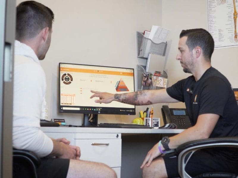 A certified personal trainer helps a gym member with a fitness consultation at a best fitness gym near me